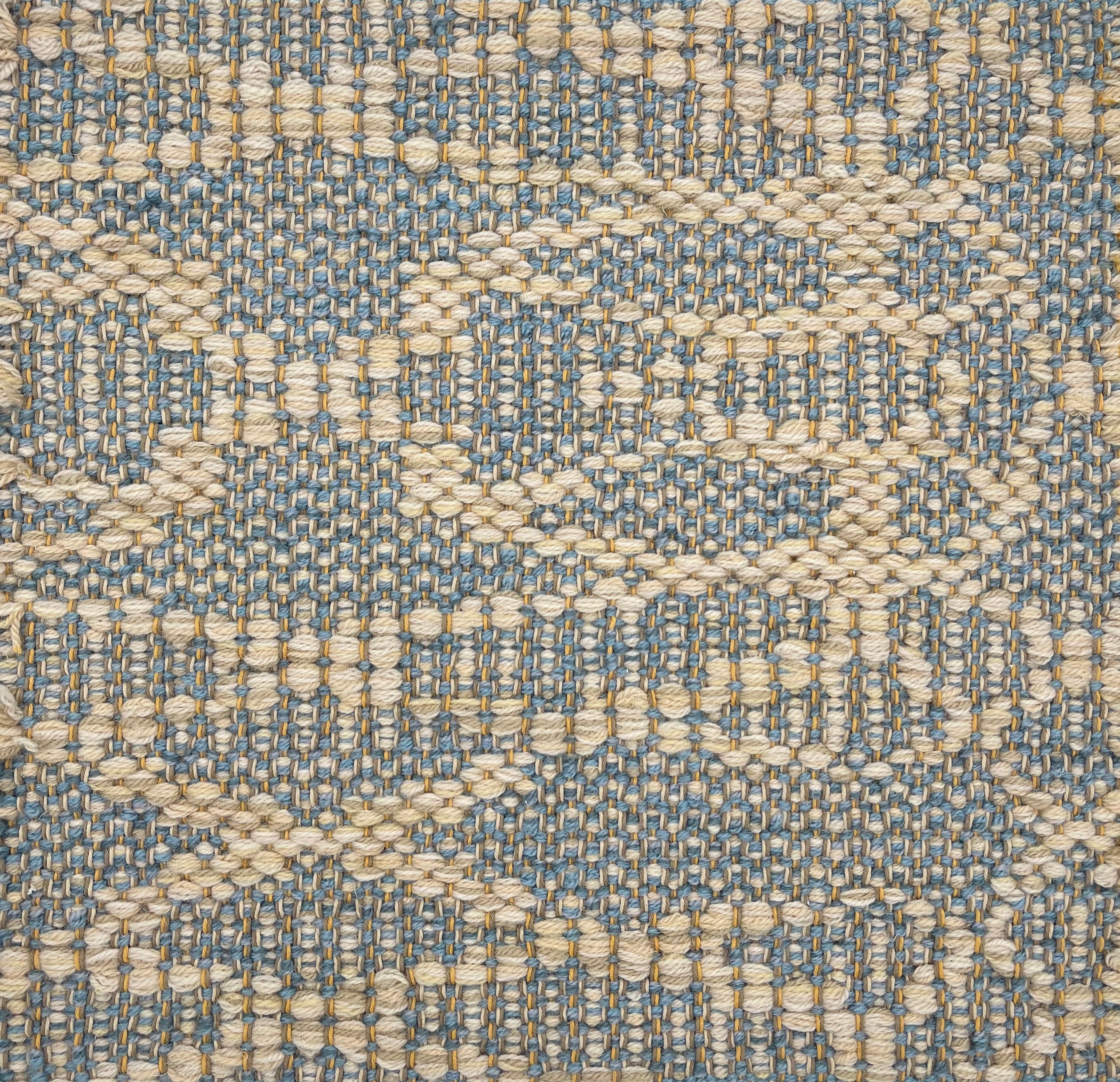 Handwoven rug detail in a geometric design in slate and beige