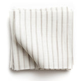 A stack of fabric swatches in a painterly stripe pattern in light gray on a white field.
