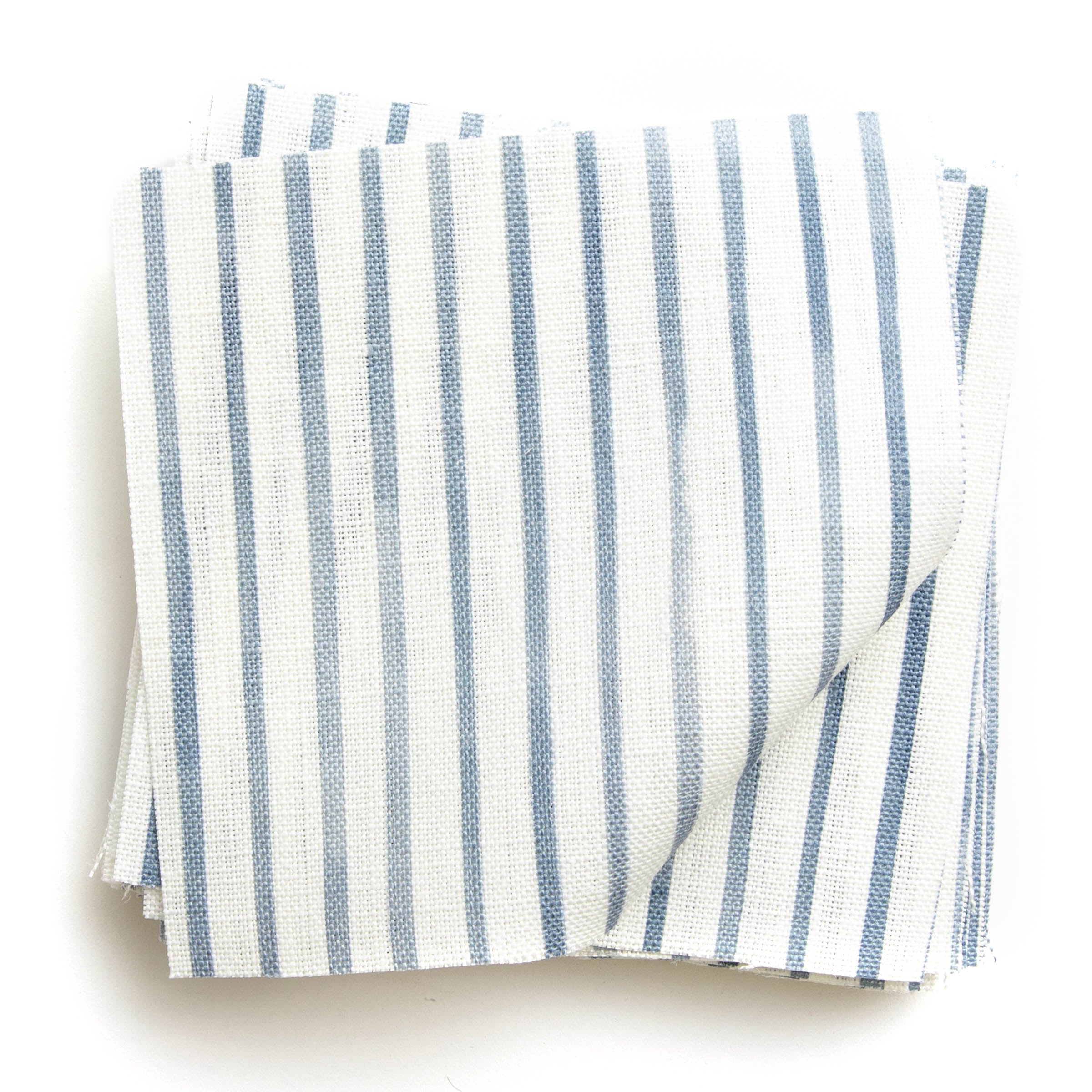 A stack of fabric swatches in a painterly stripe pattern in navy on a white field.