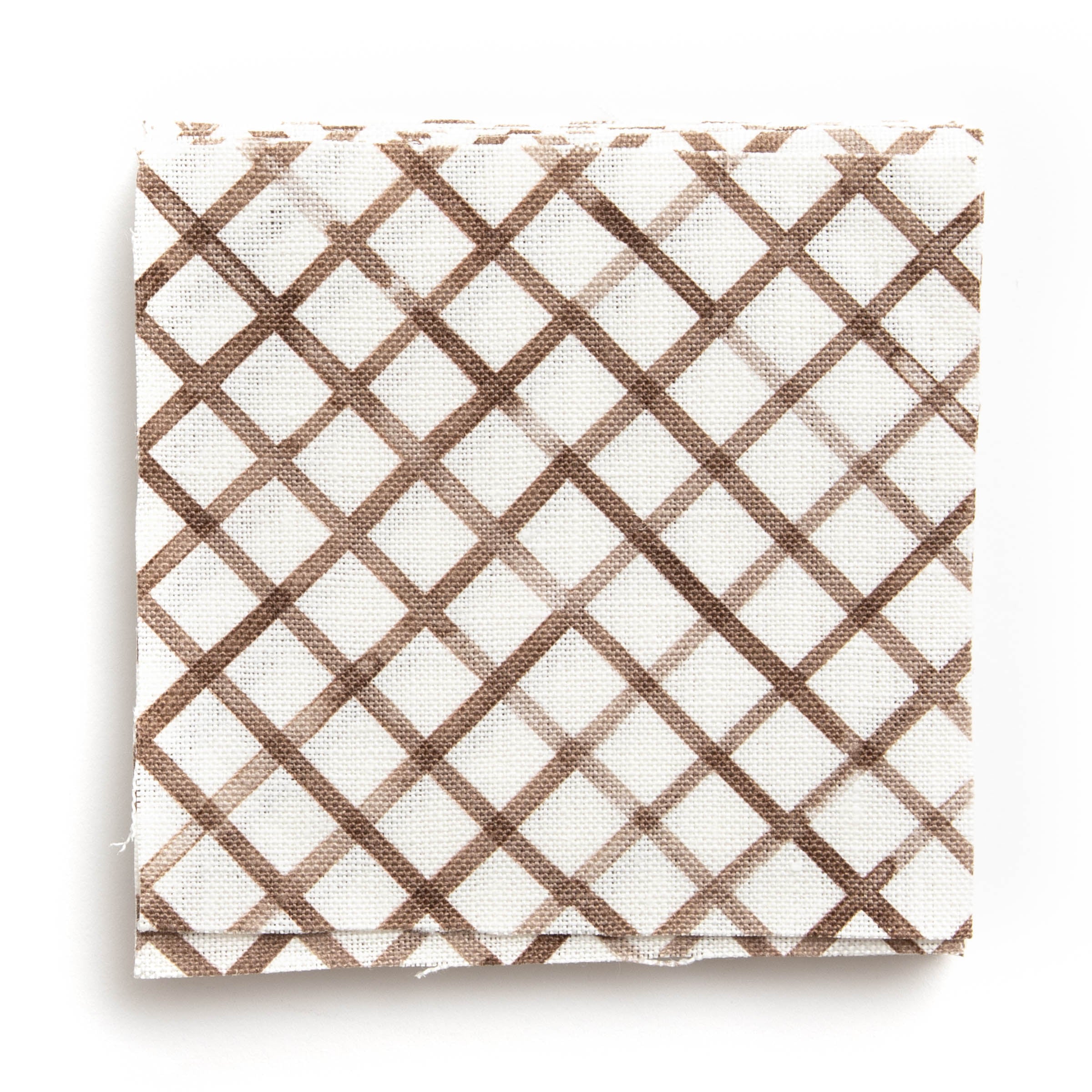 A stack of fabric swatches in a painterly grid pattern in brown on a white field.