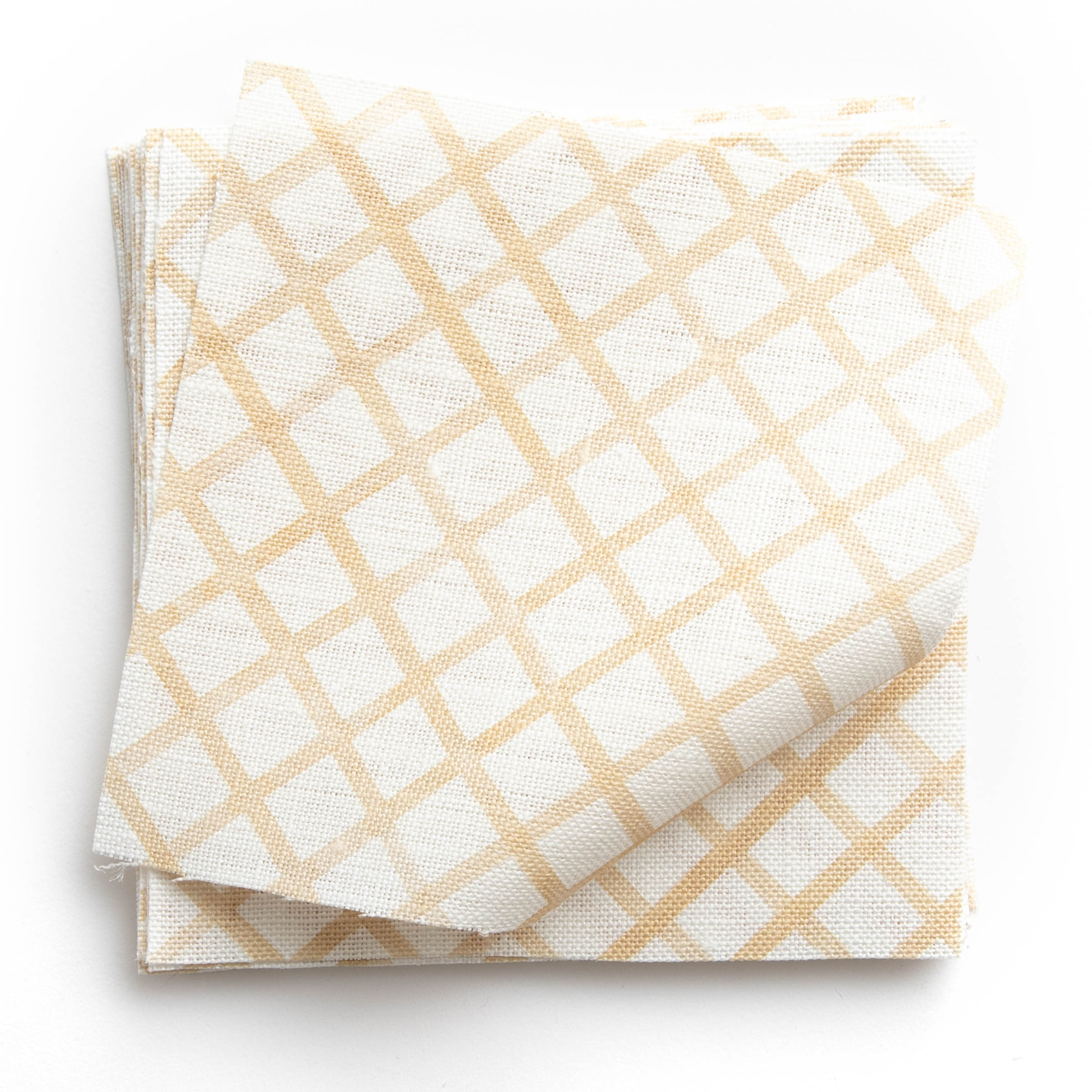 A stack of fabric swatches in a painterly grid pattern in gold on a white field.
