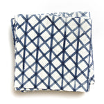 A stack of fabric swatches in an intricate striped grid pattern in navy on a white field.