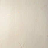 Detail of a wallpaper in an elongated paint splatter pattern in metallic gold on a cream field.