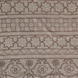 Detail of fabric in an intricate linear lattice print in black on a brown field.