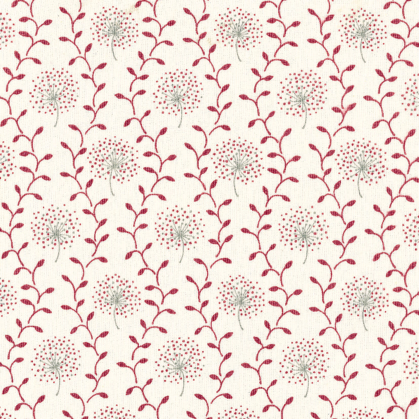 Detail of fabric in a repeating dandelion and leaf print in pink and red on a cream field.