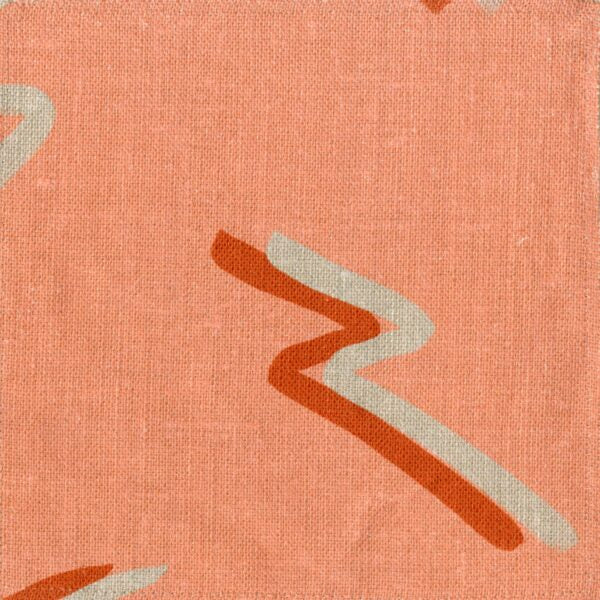 Fabric in a painterly dashed pattern in tan and red on a coral field.