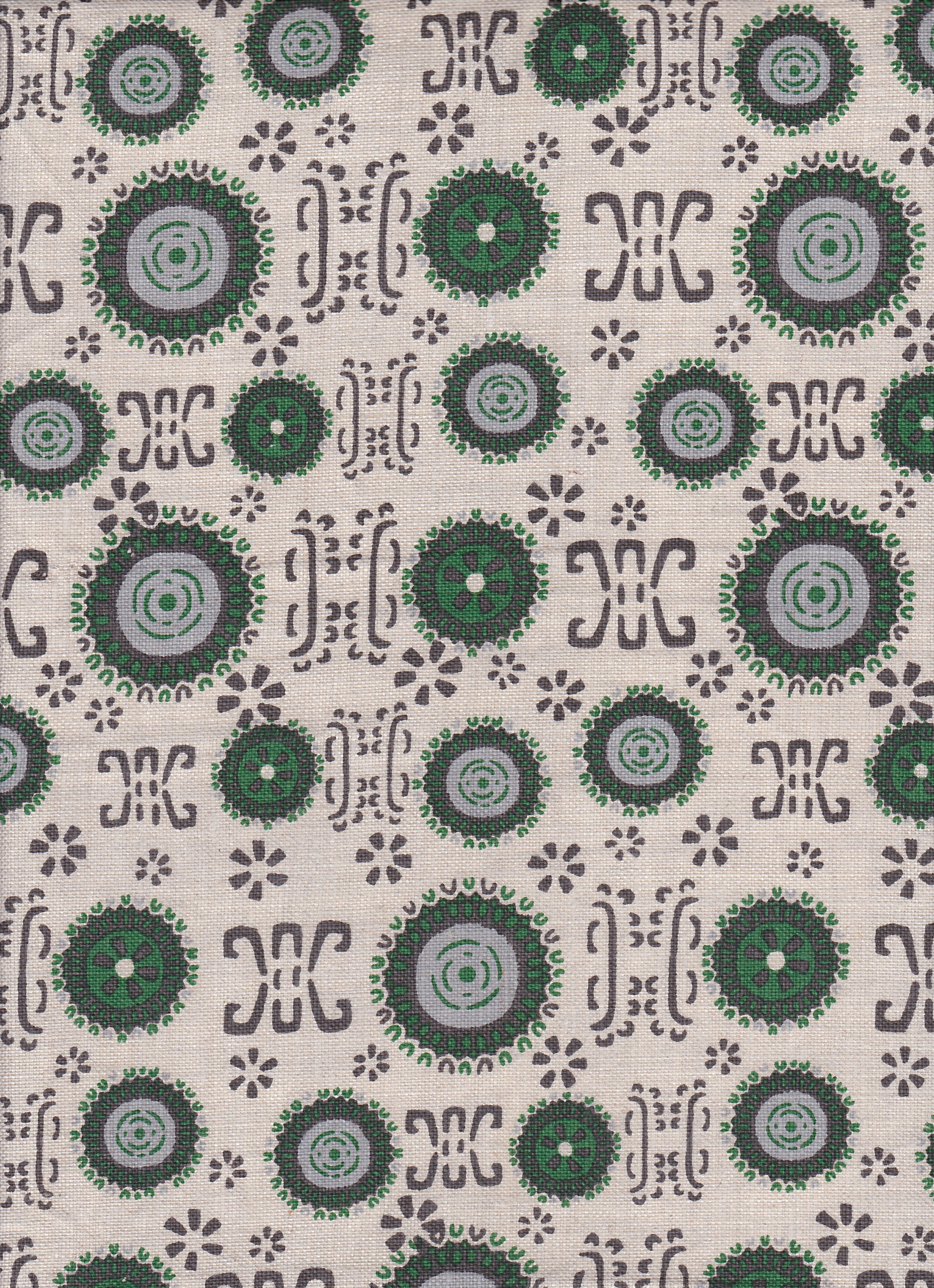 Detail of fabric in a repeating geometric shape print in shades of green and gray on a cream field.