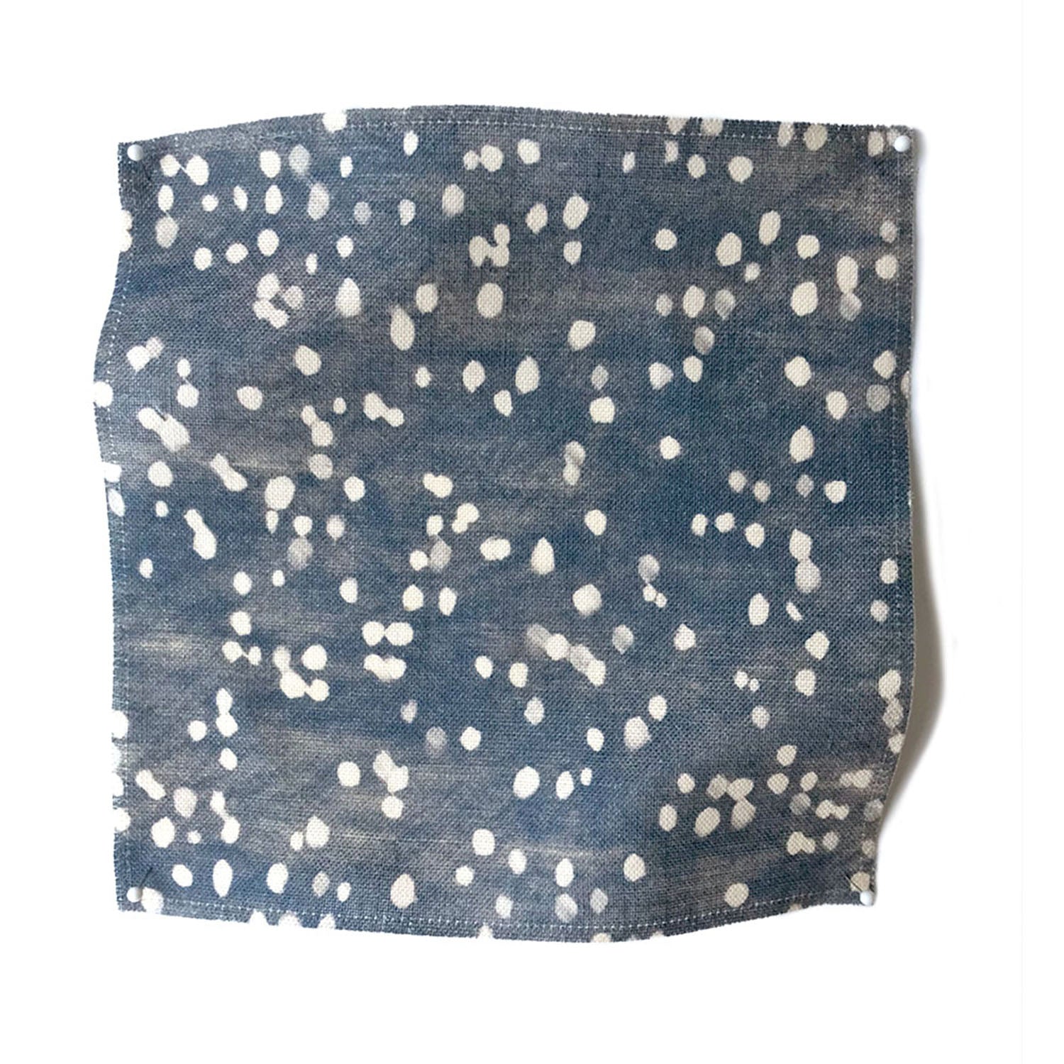 Square fabric swatch in an abstract dotted pattern in white on a mottled denim field.