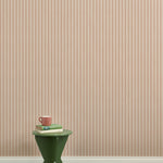 A green wooden stool with books and a mug against a Wallpaper playful hand drawn dotted stripe in blush.