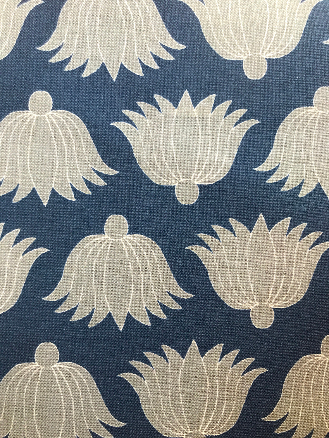 Detail of fabric in a repeating lotus print in yellow and white on a navy field.