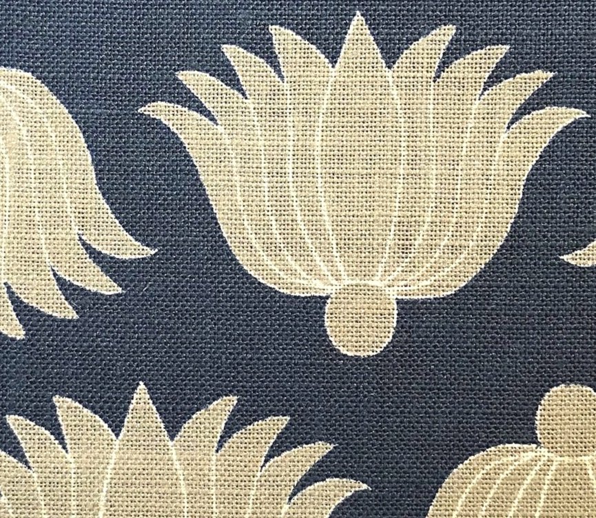 Detail of fabric in a repeating lotus print in yellow and white on a navy field.