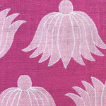 Detail of fabric in a repeating lotus print in light pink and white on a magenta field.