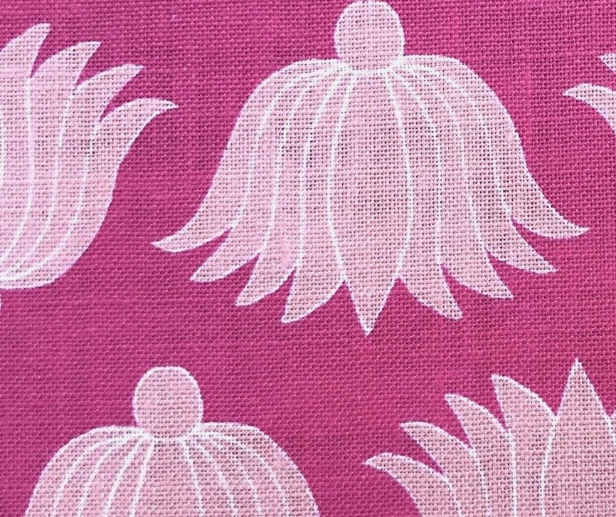 Detail of fabric in a repeating lotus print in light pink and white on a magenta field.