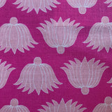 Detail of fabric in a repeating lotus print in light pink and white on a magenta field.