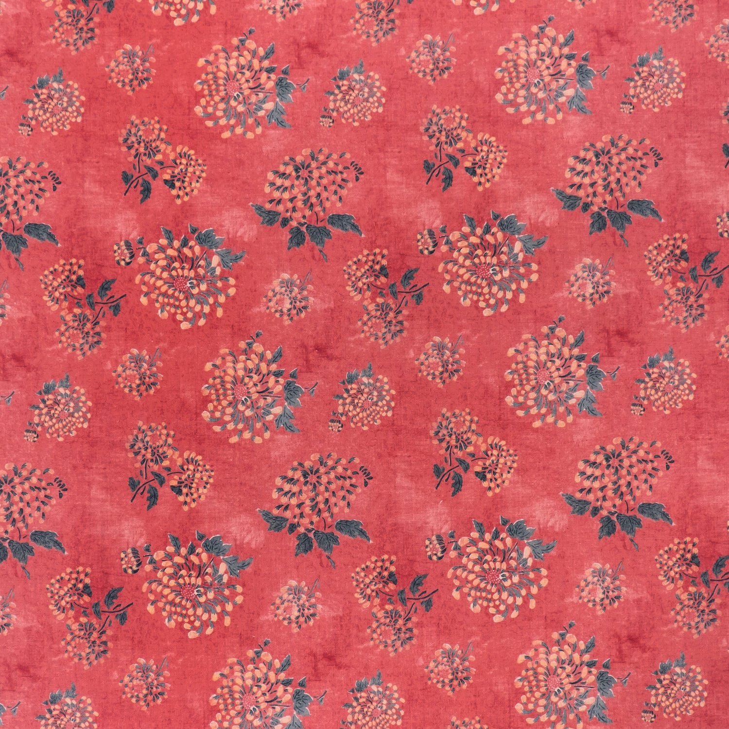 printed linen fabric in a repeating floral pattern in shades of yellow and green on a red field.