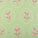 Detail of fabric in a repeating leaf print in red and cream on a light green field.