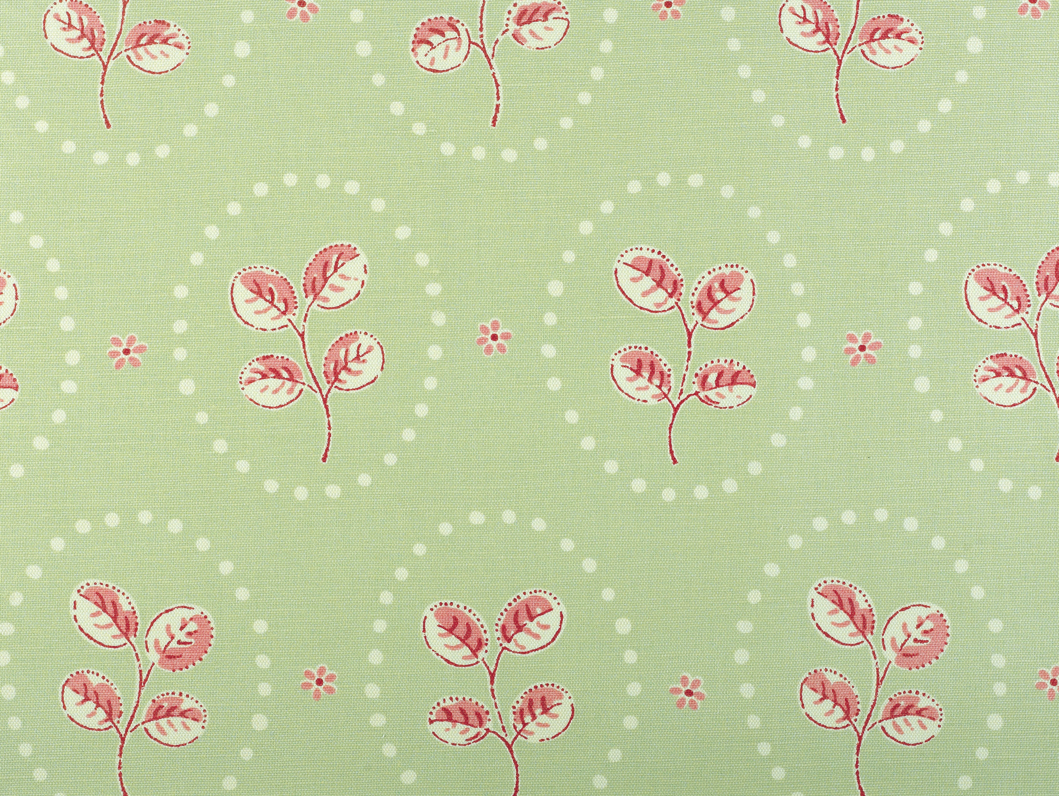 Detail of fabric in a repeating leaf print in red and cream on a light green field.