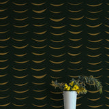 A vase of flowers stands in front of a wall papered in an abstract crescent print in brown on a black field.