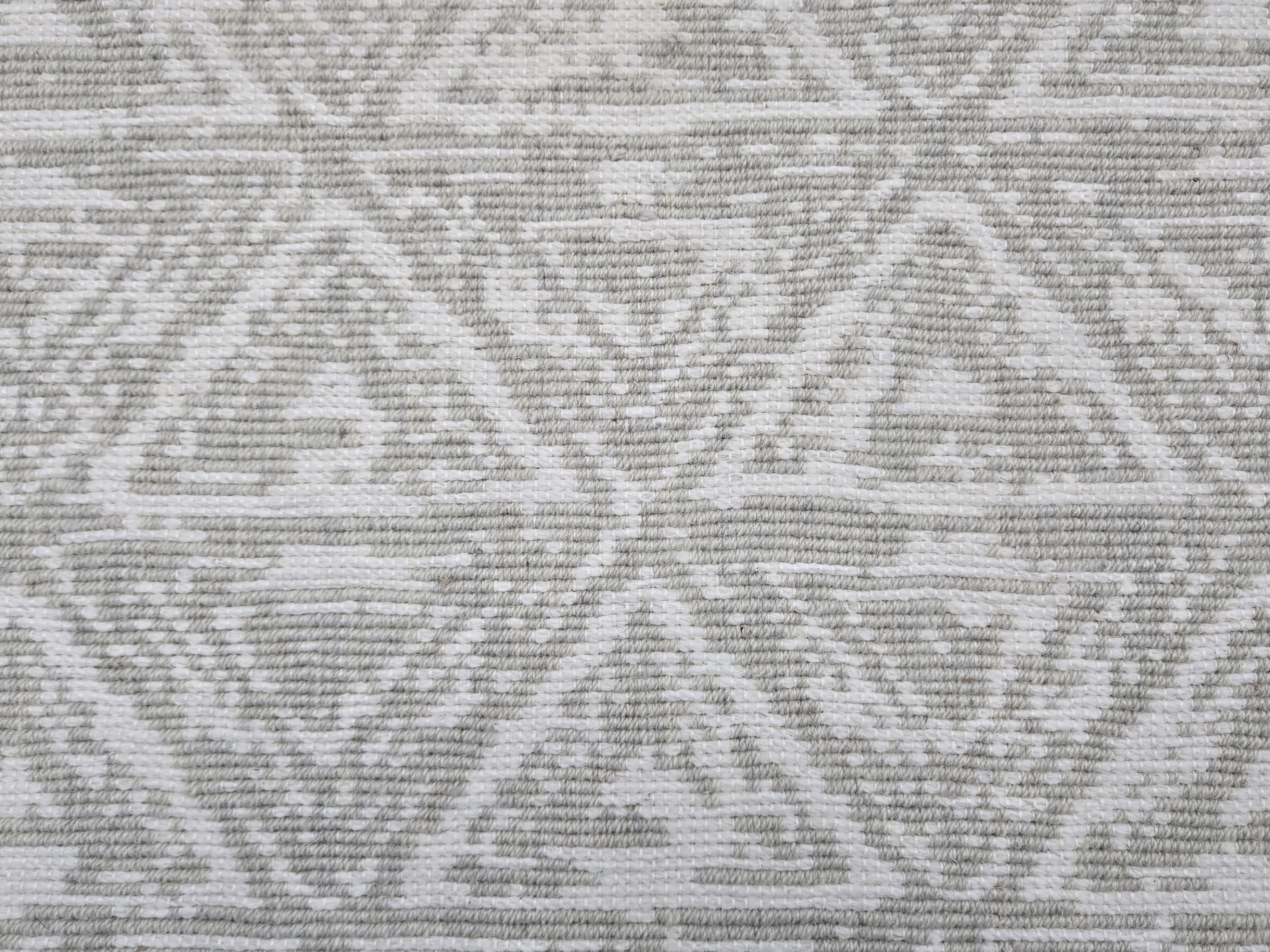 Broadloom carpet sample in a textural stacked triangle pattern in white and light grey