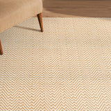 Beige zigzag patterned rug on a wooden floor with a chair partially visible.