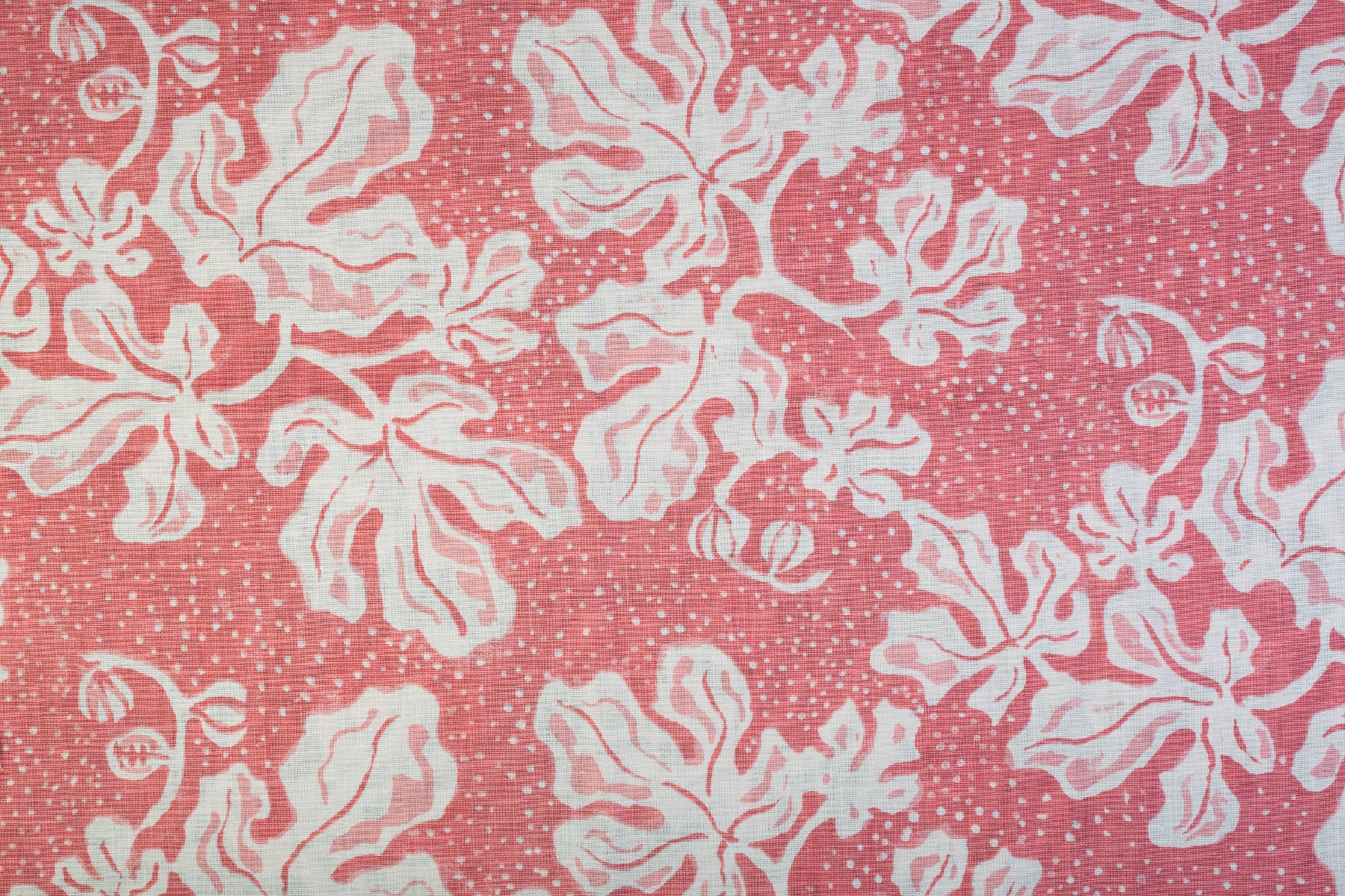 Detail of fabric in a playful botanical print in light pink and white on a pink field.