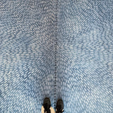 A person standing on a cowhide rug in navy with a painterly starburst overlay in blue.