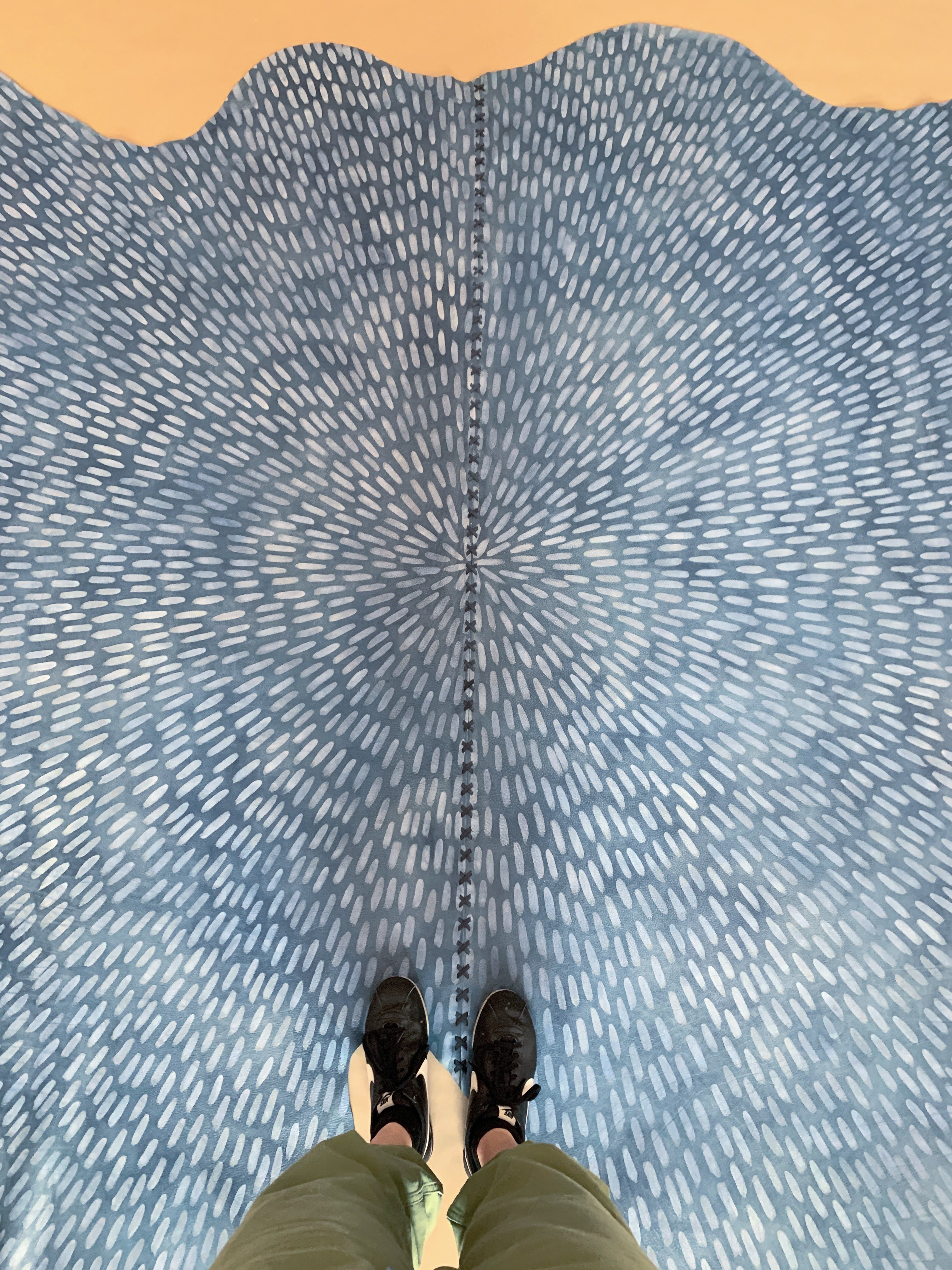 A person standing on a cowhide rug in navy with a painterly starburst overlay in blue.