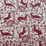 Detail of fabric in a deer, leaf and flower print in red on a white field.