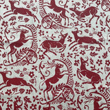 Detail of fabric in a deer, leaf and flower print in red on a white field.