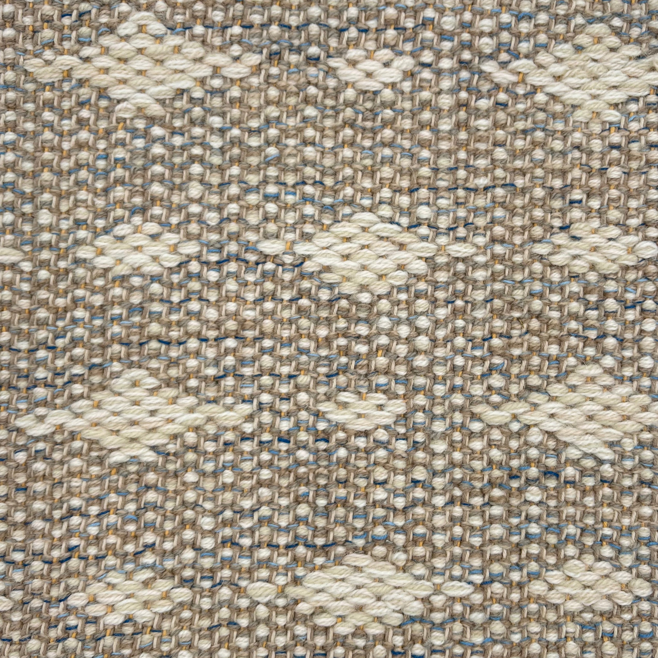 Handwoven rug detail in a contemporary spotted design in grey and beige