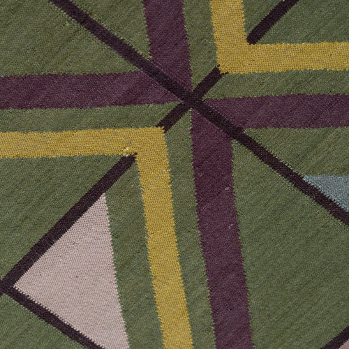 Close-up of a geometric patterned rug with green, purple, and yellow colors.