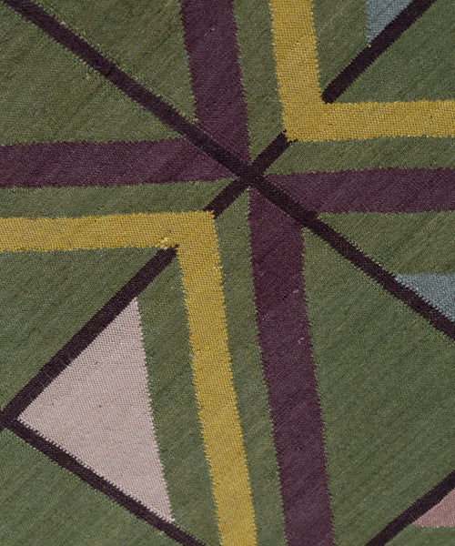 Close-up of a geometric patterned rug with green, purple, and yellow colors.