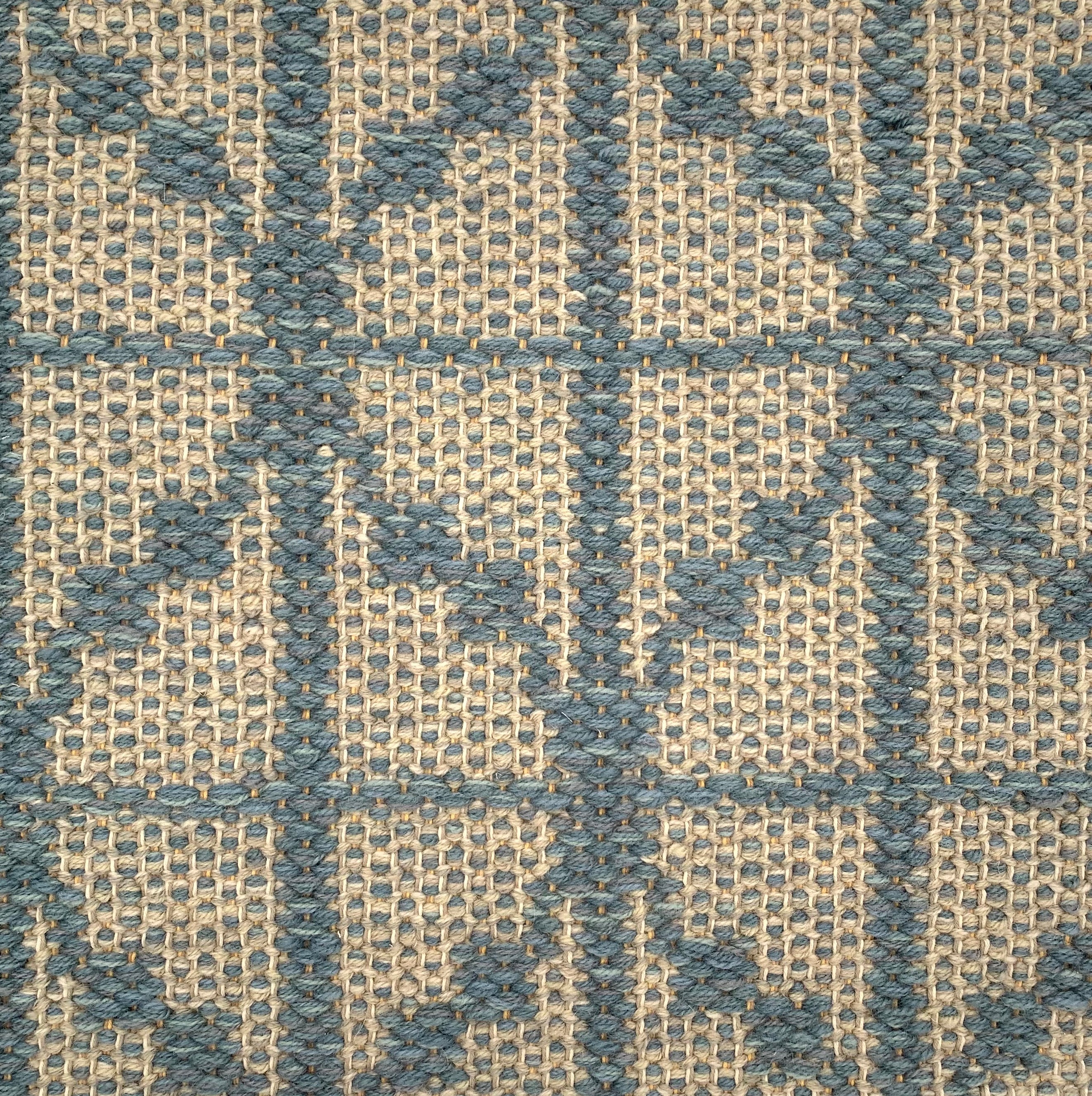 Handwoven rug detail in a diamond design in blue and beige