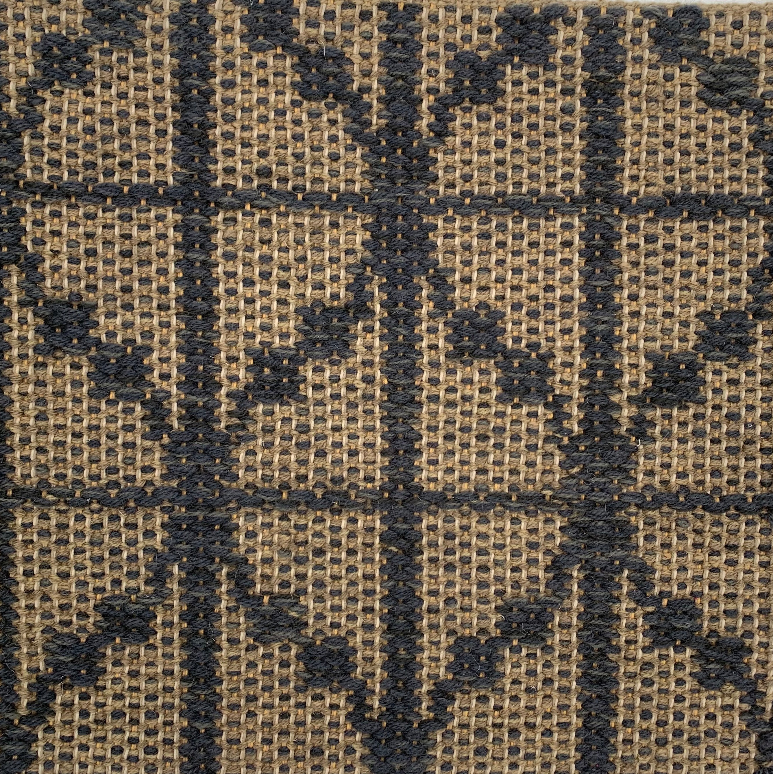 Handwoven rug detail in a diamond design in navy blue and tan