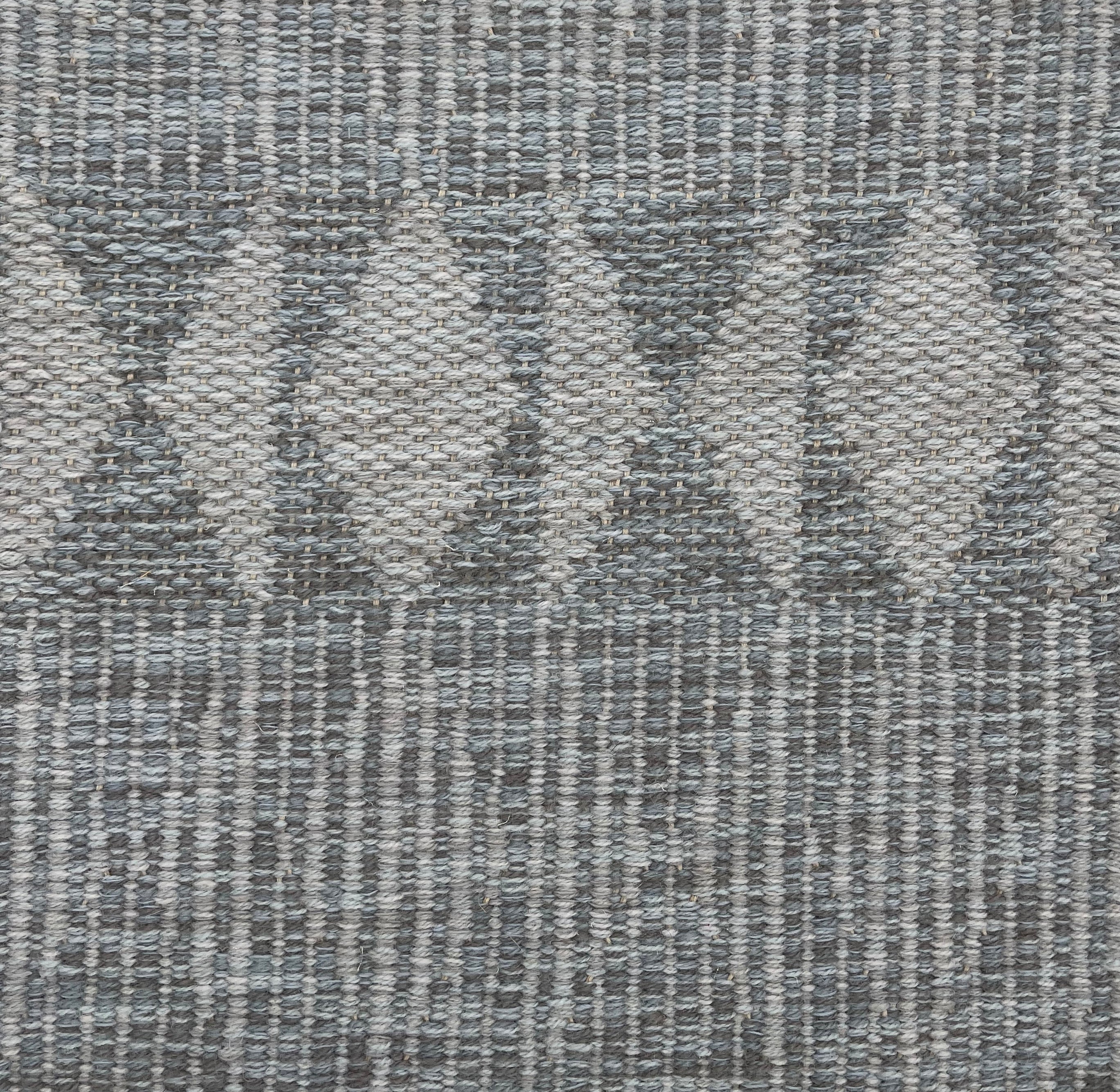 Handwoven rug detail in a diamond  design in grey 