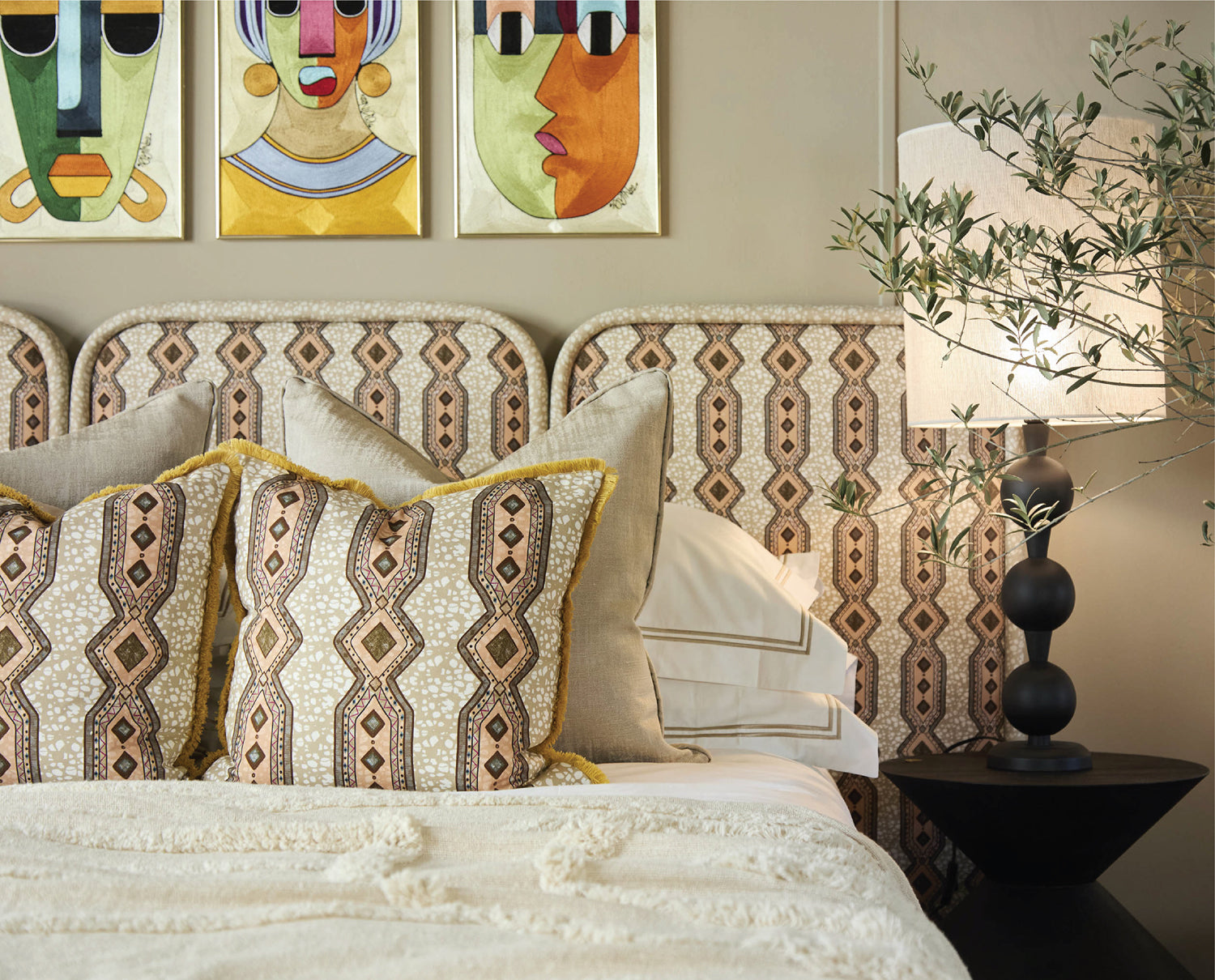 Decorative bedroom with patterned headboard, pillows, and wall art.