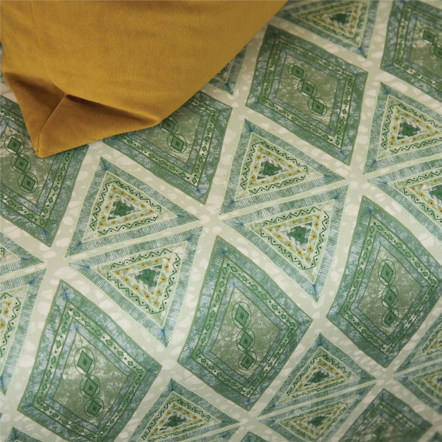 Close-up of patterned fabric with geometric design in green and beige.
