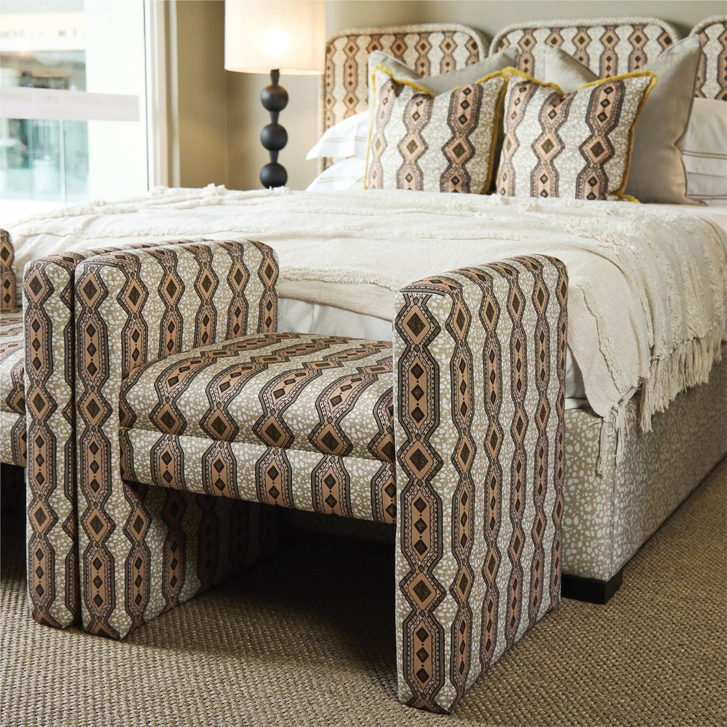 Patterned chair in front of a bed with matching bedding in a bedroom setting