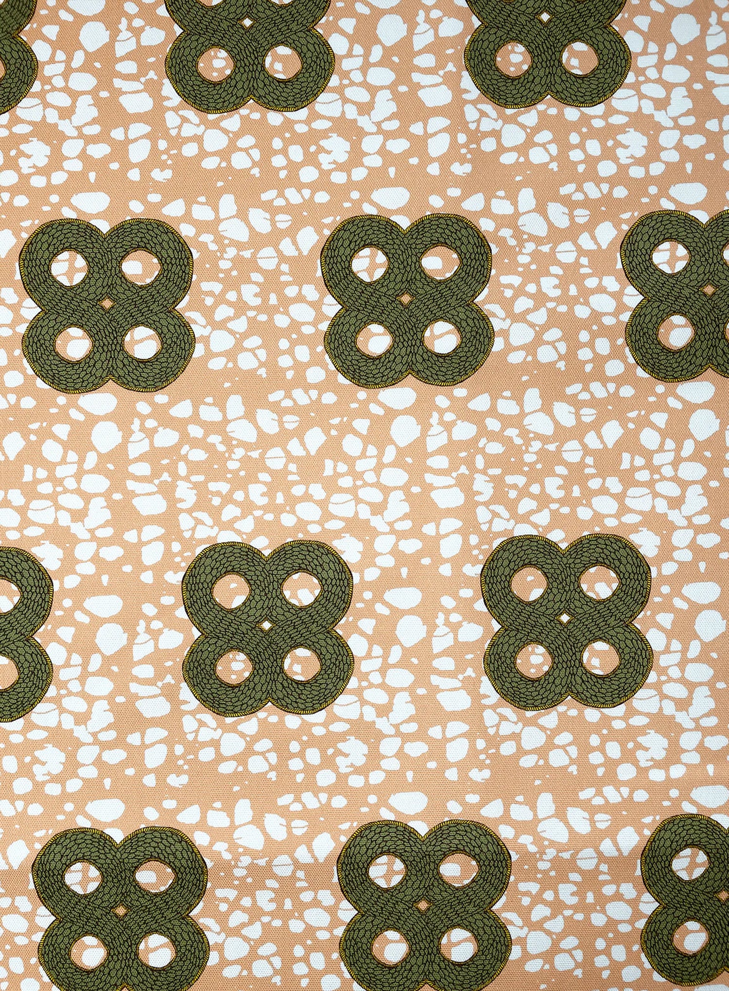 Detail of fabric in a curvilinear print in green and brown on a mottled coral field.
