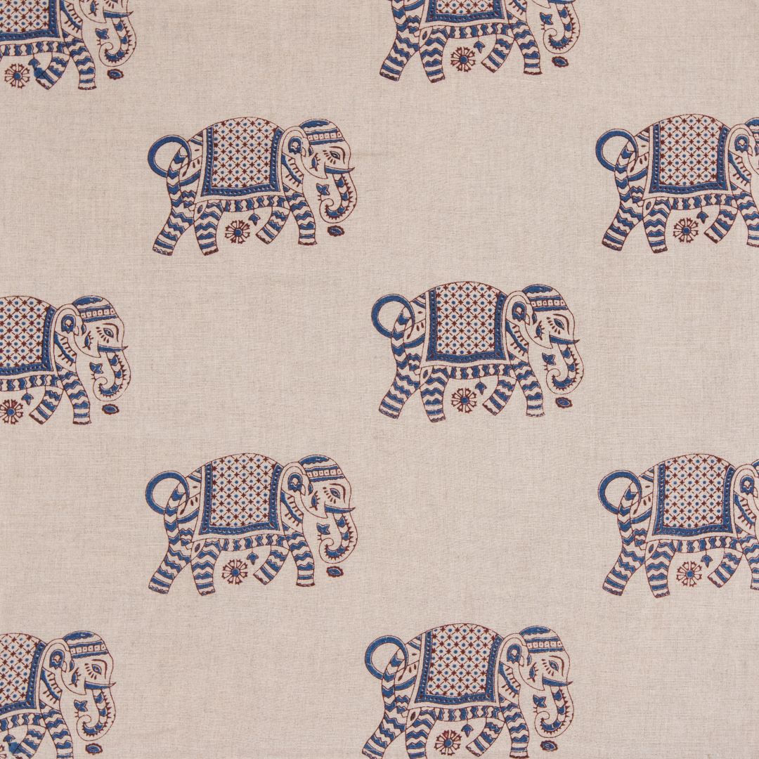 Detail of fabric in a repeating elephant print in maroon and blue on a cream field.