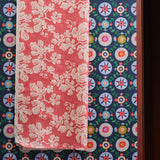 Overlapping draped fabric yardage in two playful floral prints, one on a navy field and one on a pink field.