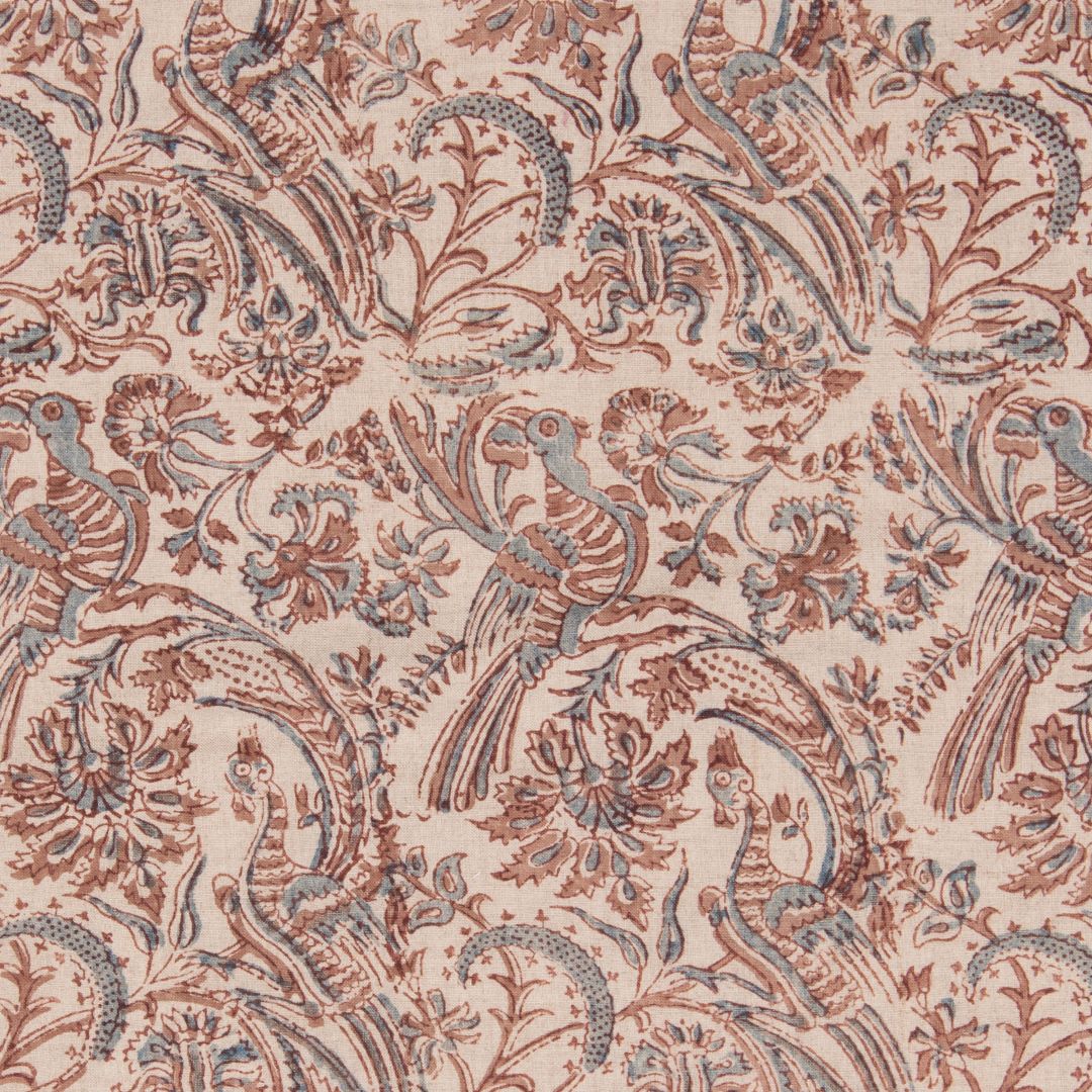 Detail of fabric in a dense bird and floral print in brown and blue on a cream field.