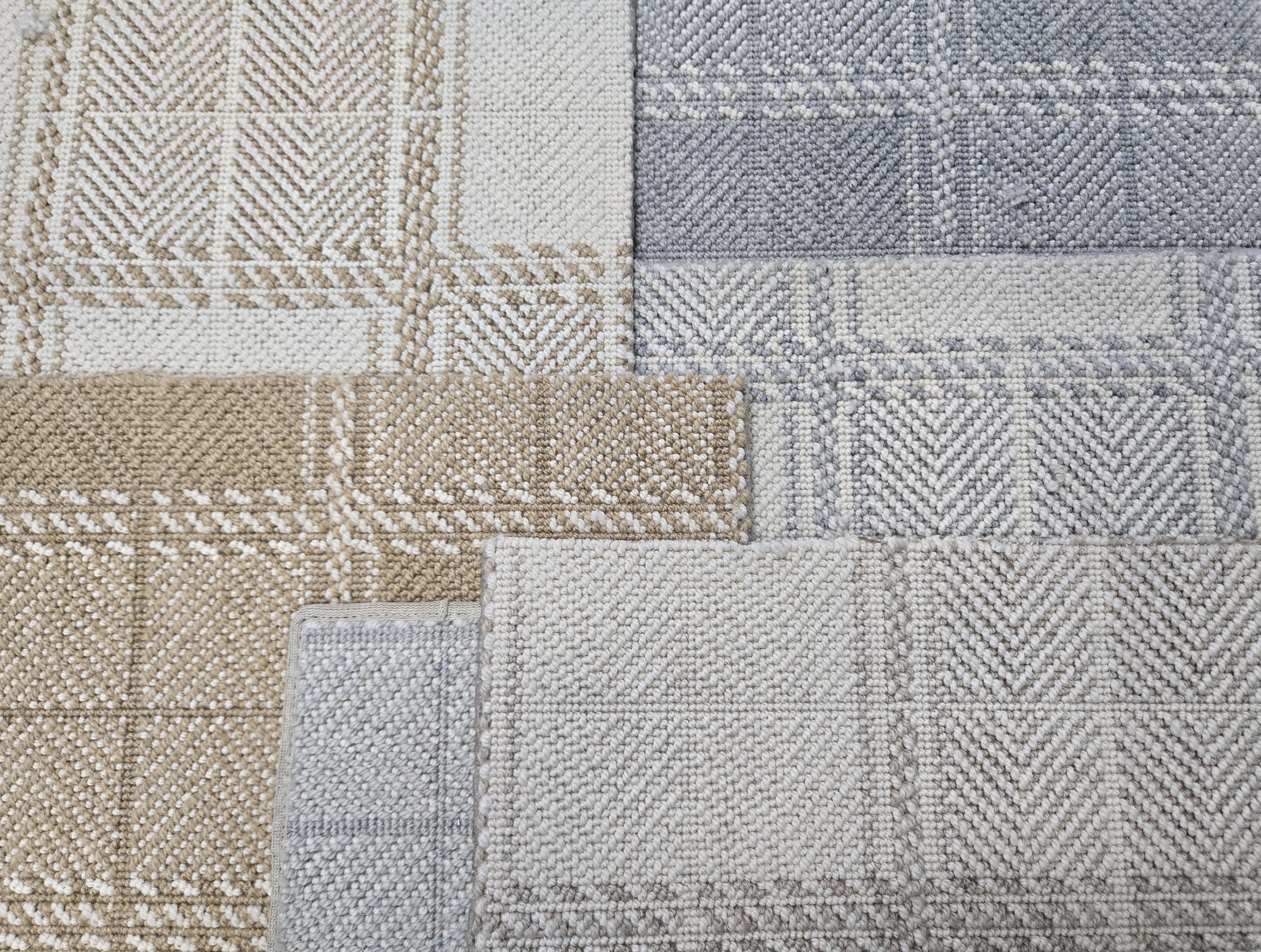 Broadloom carpet samples in a plaid pattern in a range of tan, cream, grey and blue. 