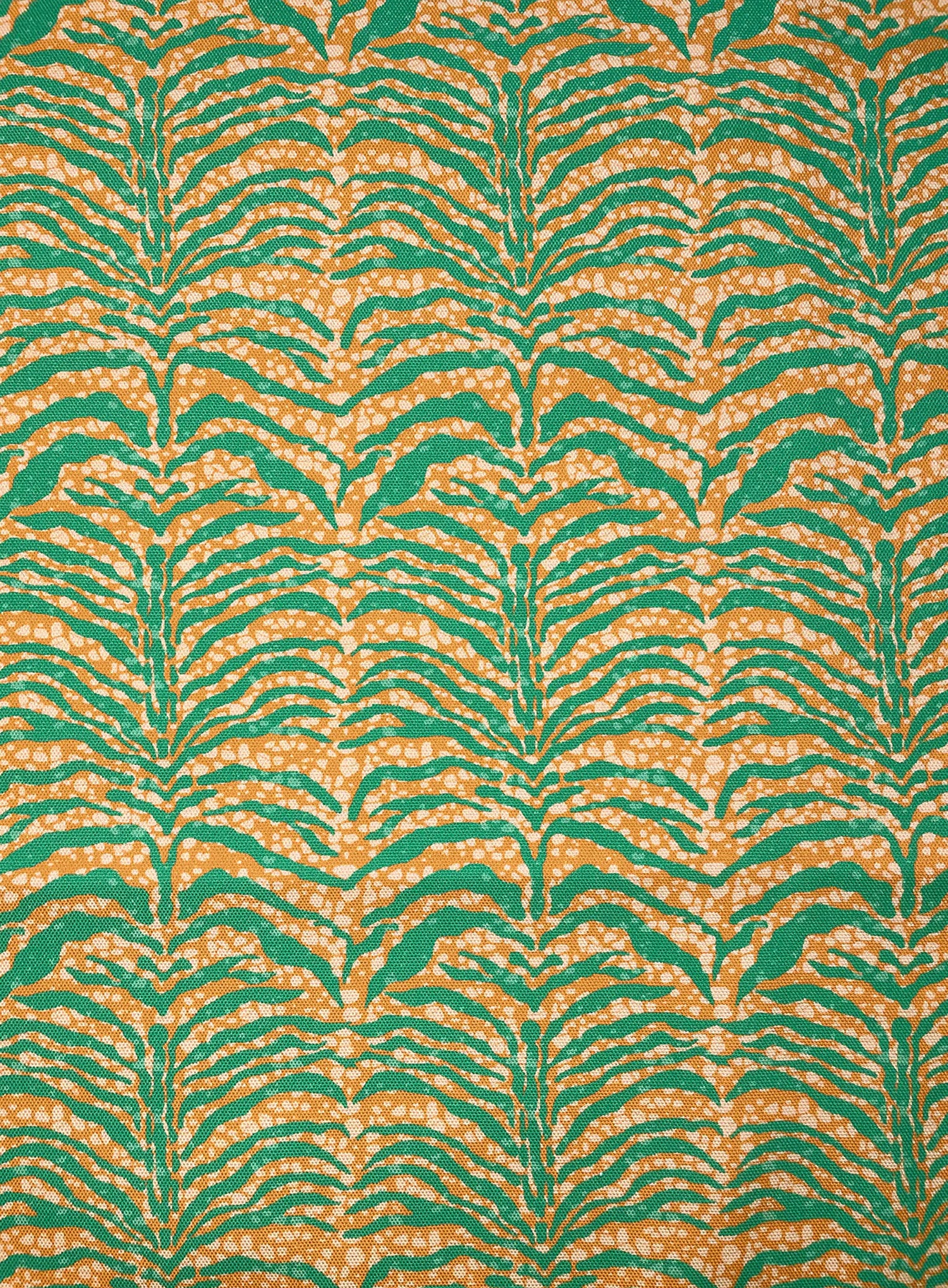 Detail of fabric in a linear botanical print in green on a mottled cream and orange field.