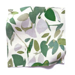 Square fabric swatch in a minimal leaf print in shades of green and gray on a white field.