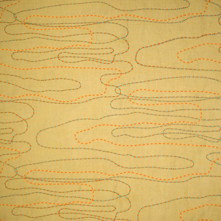 Detail of fabric in an abstract embroidered pattern in red, yellow and blue on a yellow field.