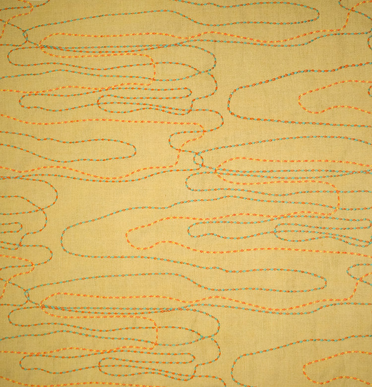 Detail of fabric in an abstract embroidered pattern in red, yellow and blue on a yellow field.