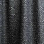 Draped fabric yardage in a textural geometric print in shades of gray on a charcoal field.