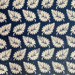 Detail of fabric in a repeating leaf print in cream on a navy field.