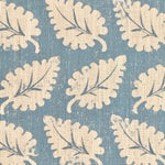 Detail of fabric in a repeating leaf print in cream on a blue field.